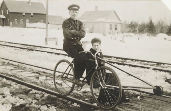 C.F. Kaufman and his wife seated on a bicycle which he adapted to run, as a three-wheeled cycle, on railroad rails.