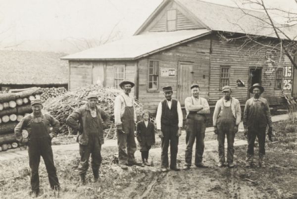 Group of men and a young boy breaking hemp at the Brigham farm.