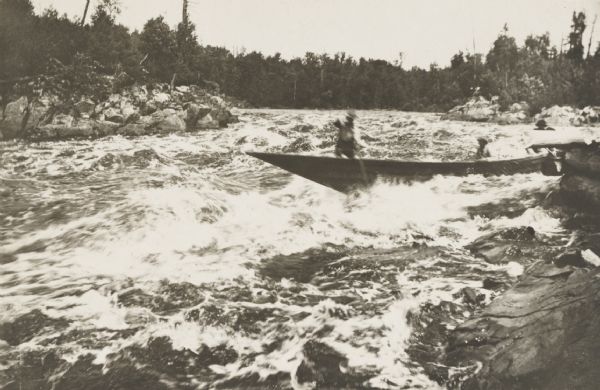 Lumbermen in a bateau descending rapids in an unidentified northern or north-central Wisconsin river.