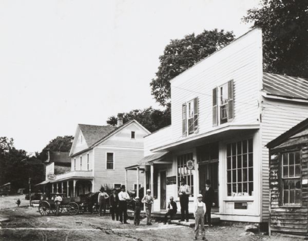 View from street of storefronts, Post Office and group of bystanders.