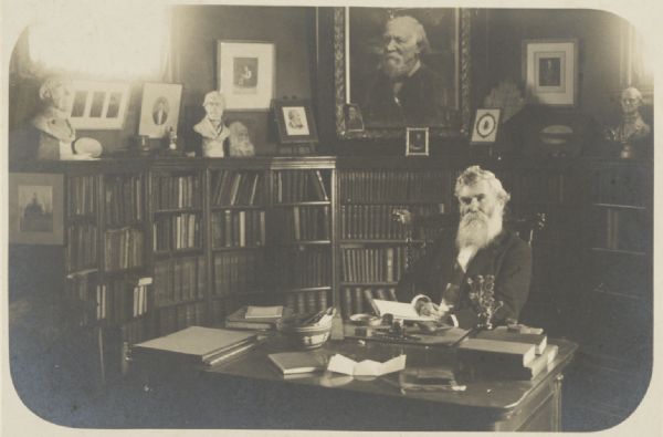 John Lloyd seated in his library surrounded by memorabilia.