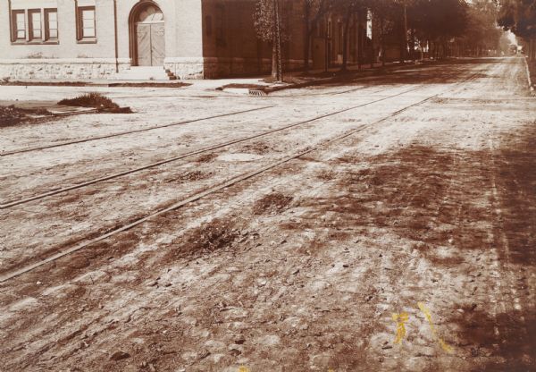 Wells Street, between 16th and 18th Streets. Record photograph for a survey of Milwaukee street conditions, made to show the wooden cedar block pavement. There are streetcar tracks, and a streetcar is in the far background.