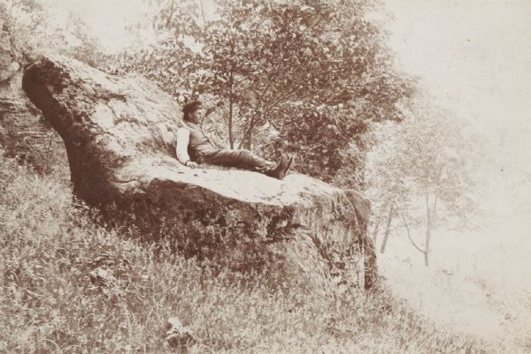 Young man sitting on a large rock called the “Devil's Chair” in Rattlesnake Hollow.