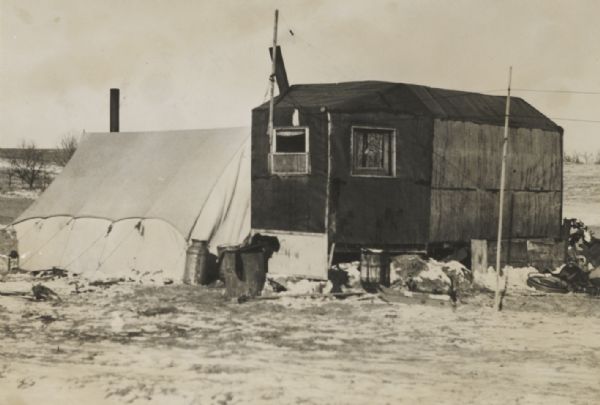 Tarpaper shack and adjoining tent.