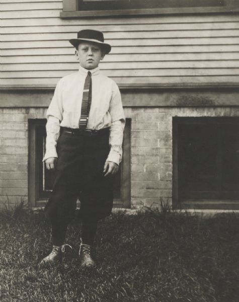 Unidentified boy posed standing in the yard in front of a frame house, probably in Hartford.
