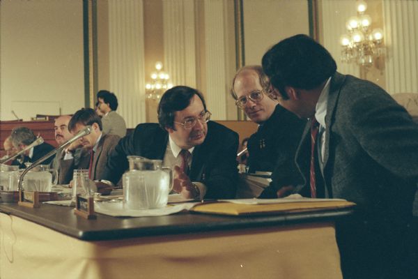 Congressman David R. Obey of Wisconsin confers with Leon Panetta, Congressman from California and head of the Budget Committee (facing away from the camera) during deliberations in 1990. Legislative aide Scott Lilly is between the two men.