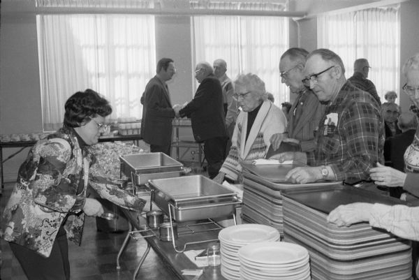 Lunchtime at a senior center in central Wisconsin. Congressman David R. Obey can be seen talking in the background. Although the location has not been identified it is thought to be Stevens Point. 
