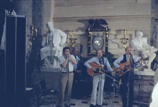 Congressman David R. Obey and his blue grass band, the Capitol Offenses, performed at many political events. It is no accident that the band chose this spot in Statuary Hall for this concert, for Senator Robert M. La Follette, Sr., whose seated statue is behind Obey, was one of his political heroes. On guitar is Scott Lilly (center), one of Obey's administrative staff.
