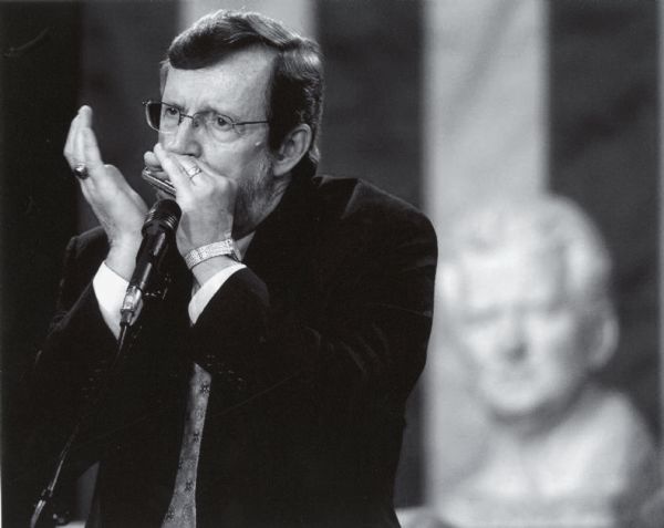 Wisconsin Congressman David R. Obey, who formed a bluegrass band known as the Capital Offenses, played the harmonica in the State Capital rotunda at the memorial service for US Senator Gaylord Nelson, with a bust statue of Senator Robert M. La Follette, Sr, looking on.