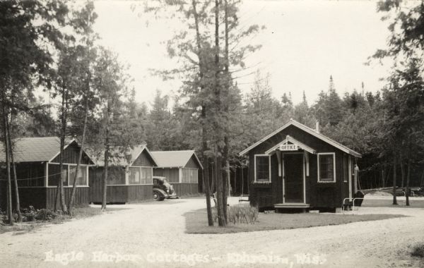 Eagle Harbor Cottages View of Eagle Harbor Cottages and the main office. An automobile is parked between two of the cottages on the left. Caption reads: "Eagle Harbor Cottages - Ephraim, Wis."