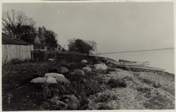 Lake Koshkonong View along rocky shoreline towards a row of cottages on the shore of Lake Koshkonong. Boats are pulled up on the right, and the far shoreline is in the distance.