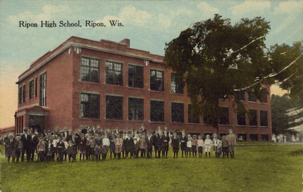 Ripon High School Text on front reads: "Ripon High School, Ripon, Wis." A two-story, red brick building, with a group of students and teachers posing on the lawn. The school is built on a raised foundation and has many large windows. There is a tree on the right with more in the background.