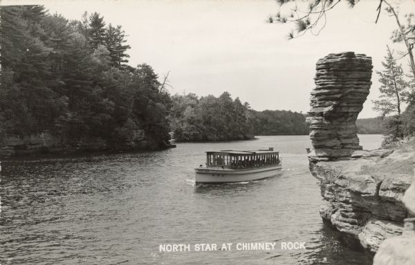 North Star at Chimney Rock Text on front reads: "North Star at Chimney Rock." The tour boat "North Star" with visitors viewing Chimney Rock, a formation on the shore of the Wisconsin River. The shoreline is filled with more formations and trees.