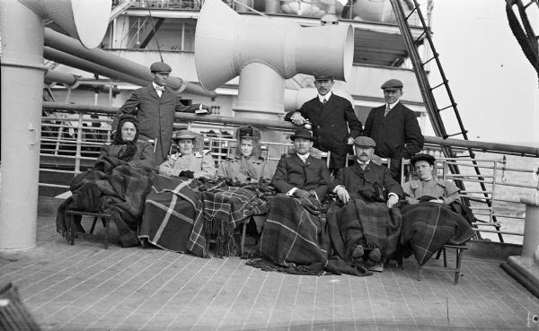 Group of men and woman on the deck of a steamship crossing the Atlantic.  Dr. Joseph Smith is seated second from the right and Mary E. Smith is seated third from the left.