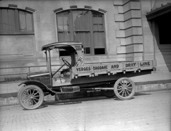 Verges Baggage and Dray Line View across street towards a mid-1920s Ford C-cab-style truck parked at the curb in front of the Chicago & Northwestern Depot, 219 S. Blair St. It is a Verges Baggage and Dray Line truck, with "No 5, Phone 805" painted on the cab.
