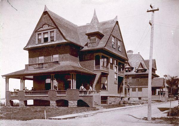 Chi Psi Fraternity House Exterior northeast view from street towards the house at 627 North Lake Street, at the intersection of Lake Street and Mendota Court. Lake Mendota is in the background on the left. A group of men are posing on the porch. The house was built in 1892 for the Chi Psi fraternity, previously located at 602 North Frances Street. Chi Psi remained here until 1909. From 1913 until its demolition in 1924-1925, the house was occupied by the Sigma Alpha Epsilon fraternity. The site was earlier used in 1853 by Daniel Gorham as the location for his steam sawmill. It was replatted for residential use in 1890.