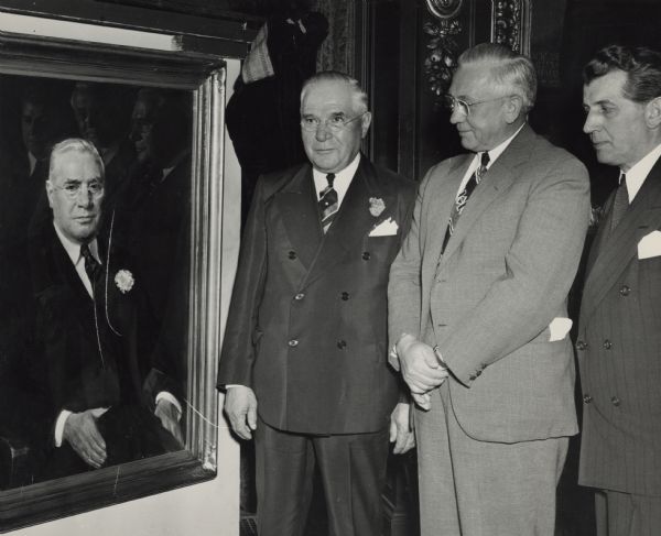 Julius Heil with his Portrait Painting Julius P. Heil, Wisconsin's 30th governor, stands next to his portrait painting with two other men. Heil wears the same tie and lapel pin as in his painting.