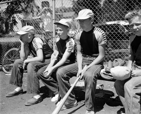 "Play Ball" Echoes Through City Baseball players from the Dairy Queen team wait their turn at bat. Shown left to right are: Robert Larson, Neal Darazio, and Peter Mery.