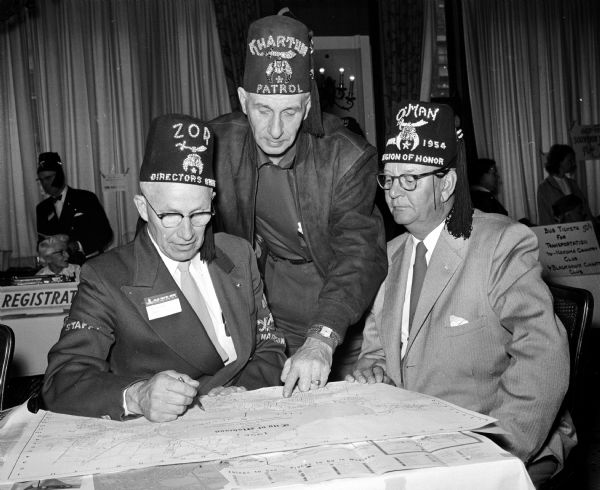 Midwest Shrine Convention Charles A. Olson, tours chairman, describes the planned tours for visiting Shriners and their wives at the Midwest Shrine Convention in Madison. Looking on are Les Kitt of Winnipeg, Canada (center) and I.G. Olson of St. Paul, Minnesota.