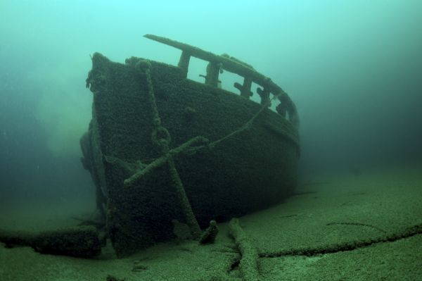 The Port Anchor of the Schooner <i>Home</i> Underwater view of the port anchor on the schooner <i>Home</i>. The anchor and chain are resting against the port side of the ship near the bow, partially submerged in the lake bed.