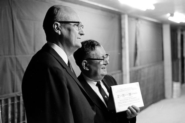 Fred H. Harrington Inaugurated as University of Wisconsin President President of the University Board of Regents Jacob F. Friedrick presenting Fred Harvey H. Harrington with an excerpt from the minutes of the Special Meeting of the Board of Regents of the University of Wisconsin, Monday, August 6, 1962. "Fred Harvey Harrington be elected President of the The University of Wisconsin effective August 6, 1962 and that he have the usual prerequisites of the office of the President of the University..."