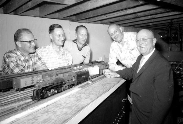 The first official contribution to the 1957 United Givers' Fund is made by the Four Lakes Model Railroad Club. On the far right accepting the donation check is campaign chairman, C. N. Goulet (of 4009 Birch Avenue). Members of the club shown on the other side of the model train are (left to right): Russell West Sackett (4313 Critchell Terrace), treasurer; William Schweinem (325 West Mifflin Street), president; Earl Carpenter (4801 Ruth Street); and Vincent Doll (2222 South Park Street).    
