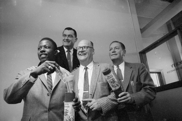 Hank Aaron Appears Before the Rounder's Club Milwaukee Braves outfielder, Hank Aaron, talks to the Rounder's Club and makes a donation to the Wisconsin State Journal's Empty Stocking Club. Shown with Aaron are (left to right): Parker Daggett, Miller Brewing Company; Herman Isenbeck, Miller Brewing Company; and Orville (Rusty) Syse, Middleton.