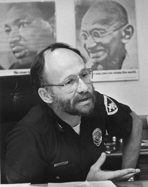 David Couper Madison Police Chief David Couper in his office with posters of Martin Luther King, Jr. on the left, and Mahatma Gandhi on the right.