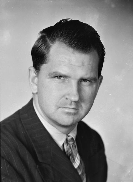 Sid Studio Portrait Head and shoulders studio portrait of Sid wearing a suit and tie.