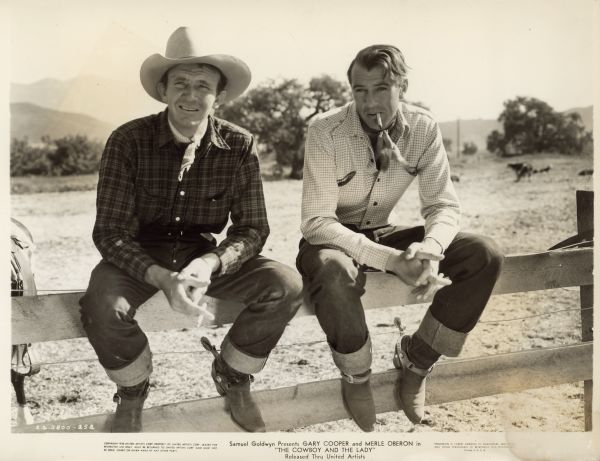 Gary Cooper and Walter Brennan Gary Cooper and Walter Brennan sit on a wooden fence on the set of the 1938 film "The Cowboy and the Lady." both are dressed as cowboys. Cooper has a cigarette in his mouth and Brennan holds a cigarette in one hand.