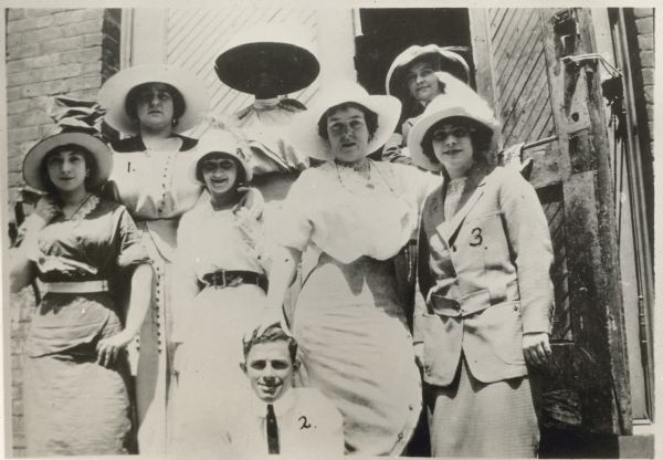 Mae West and friends Mae West poses with a group of friends sometime in the 1910s or early 1920s. Besides West, the group consists of six women, including a Black woman, and a man. All the women are wearing hats. West is on the right side of the photograph marked with the number 3.