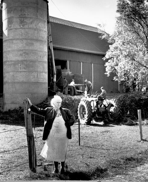 Mrs. Mary Shaughnessy standing in front of barn where men are loading the silo. Her farm was on the site where Granville School was later built.