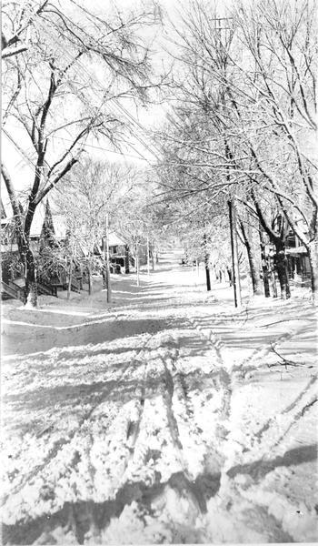 Snow on Butler Street Winter scene of an unplowed, snowy Butler Street, with tire tracks and snow-covered trees.
