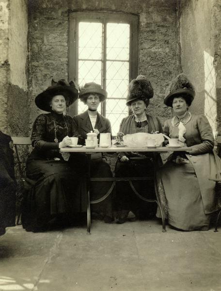From left to right Ida Fisk, Dorothy Purchas (b. 1891), Emma (Thorsen) Purchas (1862-1944), and Ethelinda (Thorsen) Johnston (1856-1947) of Milwaukee, Wisconsin in Germany on vacation.  At this time Emma and Dorothy resided in England.

Wearing dresses and elaborate hats, the ladies are posed inside a rustic stone building having tea.

The photograph dates from 1910-1913.