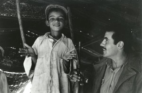 An Algerian Bedouin boy with a soldier. The boy is pledging that he will kill his father "with joy" if the father should serve the French forces in the guerilla warfare. The soldier approving his declaration is from the FLN rebel Scorpion battalion to which Dickey Chapelle was attached.