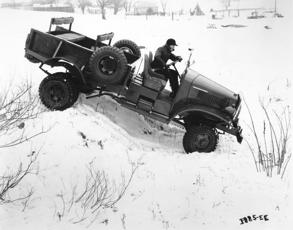 Man testing an International military M-2-4 4x4 truck on a snow-covered hill.