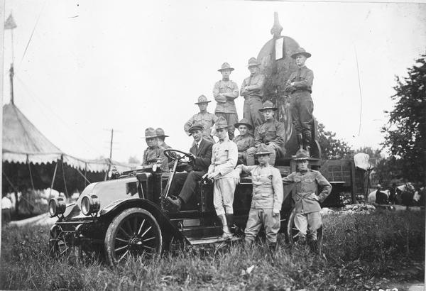 World War I soldiers standing in front and on the back of an International truck with a recruiting poster.