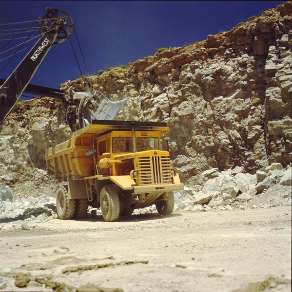 Color photograph of an International 65 payhauler dump truck in a quarry with shovel.