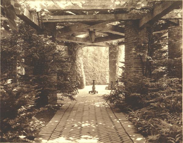 The grounds at "Walden", residence of the Cyrus McCormick, Jr. family, showing an outdoor table and two chairs under a pergola.