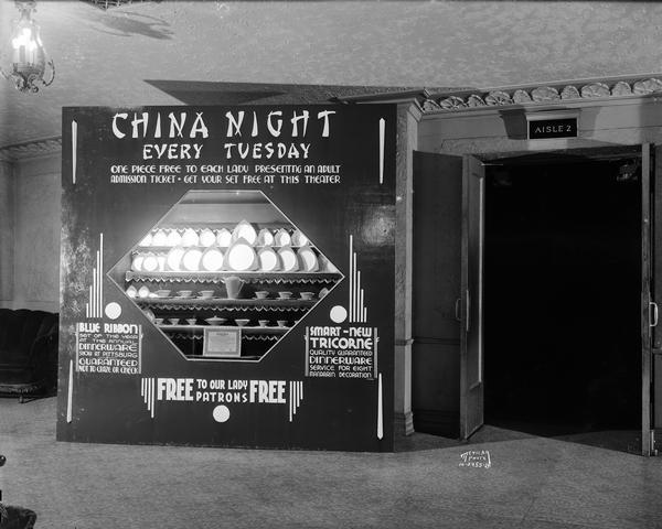 Promotional display of Salem china, Tricorne pattern, in the lobby of the Eastwood Theatre, 2090 Atwood Avenue. The sign reads: "China Night Every Tuesday - One Piece Free to Each Lady Presenting an Adult Admission Ticket - Get Your Set Free at this Theater." "Blue Ribbon Set of the Year at the Annual Dinnerware Show at Pittsburgh - Guaranteed not to Craze or Check."