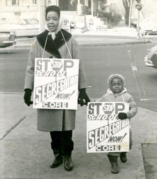 A woman and child carry CORE picket signs protesting school segregation.