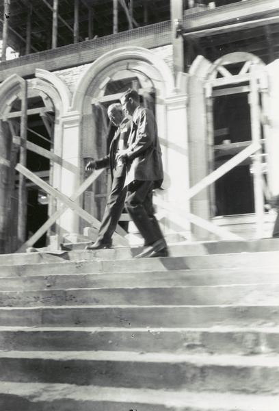 Colonel Charles Lindbergh walking along steps at the Memorial Union, at the University of Wisconsin-Madison. Mr. Carl Johnson (left) of the Union Committee made the presentation. The building appears to be under construction.