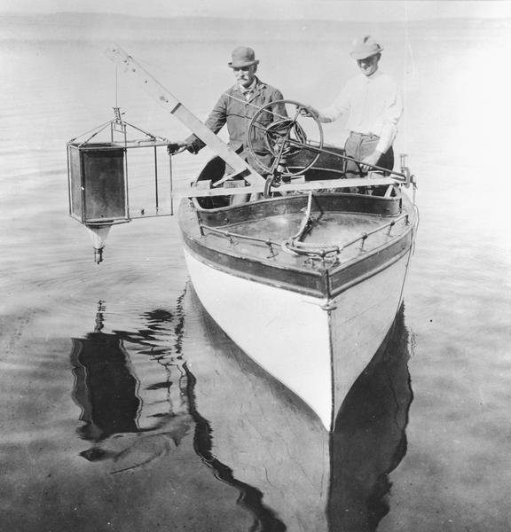 Edward A. Birge and Chancey Juday with plankton trap in Lake Mendota. From album of photographs relating to the research in limnology conducted at Trout Lake, and elsewhere by Edward A. Birge, University of Wisconsin-Madison.