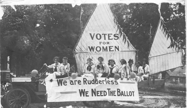 Members of the Oshkosh Equal Suffrage League in their 4th of July float made up with a sail boat. Banners read "Votes for Women" and "We are Rudderless, We Need The Ballot." Identified in the picture are Lilian Clark, Bernice Mocke, Helen West, Gertrude Hull, Josephine Van Slyke, Hester Lancaster, Katherine Forward, Jennie Robinson, and Maria Hilton.
