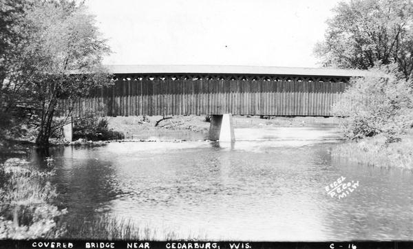 Exterior view of the last covered bridge in Wisconsin. Caption reads: "Covered Bridge Near Cedarburg, Wis."