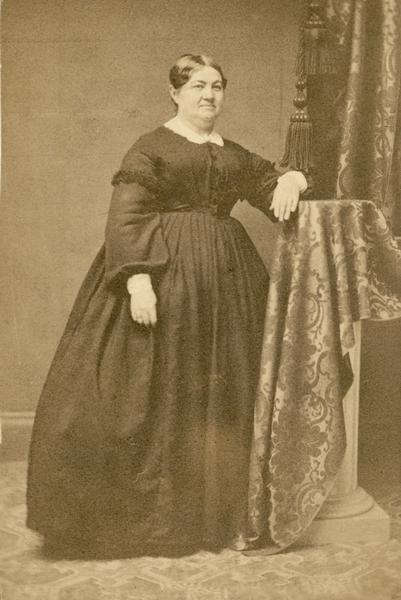 Formal full-length studio portrait of Elizabeth Therese Baird wearing a long, black dress.