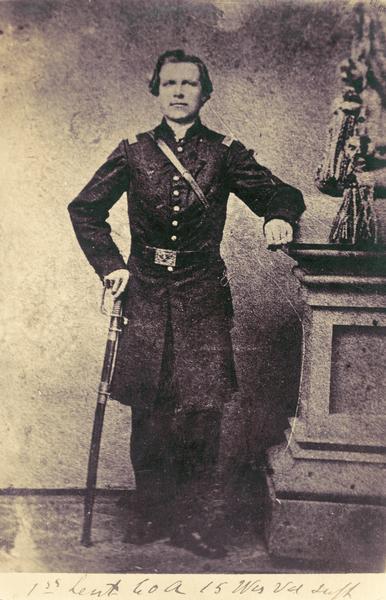 Full-length studio portrait of Civil War soldier Nils (Niels) J. Gilbert, Company A, of the 15th Wisconsin Infantry, believed to have been taken in October 1864 at Chattanooga, Tennessee.  He is in uniform and leaning on his sword. He entered service on 2 October 1861 as a 1st Sgt, was promoted to 1st Lt. on 19 October 1864, and mustered out on 20 December 1864 when his term expired.