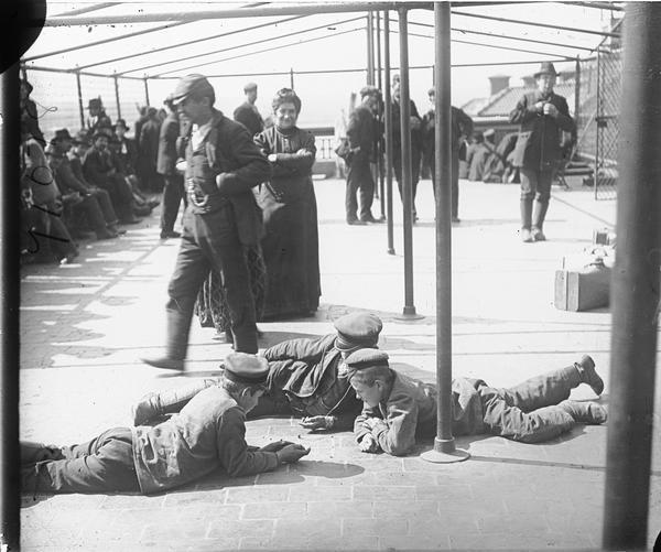 Immigrants being detained at Ellis Island. Three boys lay on the ground together.