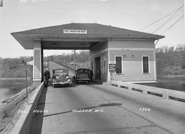 Toll House in Hudson showing two cars passing through. Caption reads: "Toll House, Hudson, Wis."