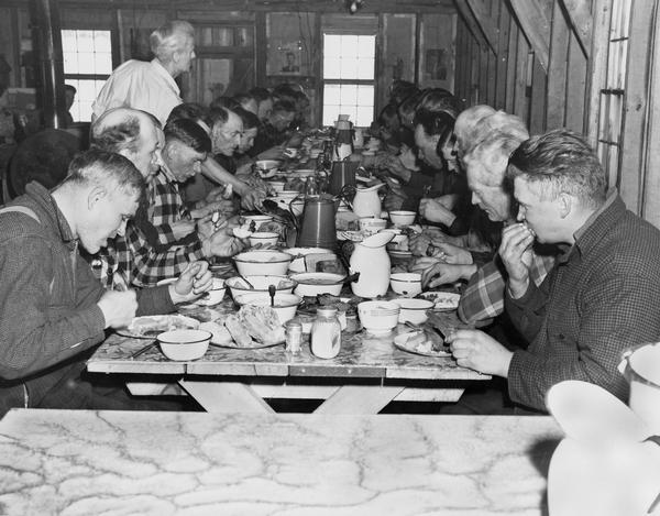 Lumberjacks eating in a cook shanty; probably early twentieth century.